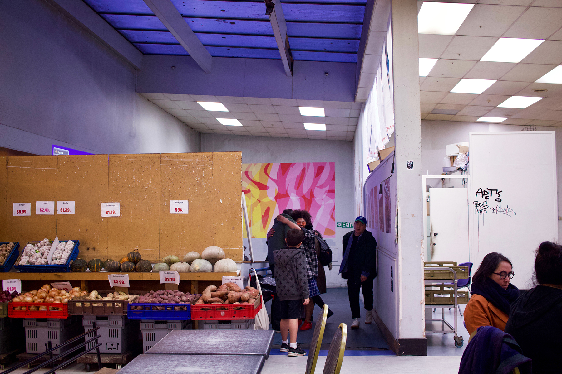 Mercury Plaza: Origins + New Beginnings next to crates of vegetables from New Gum Sarn Supermarket.