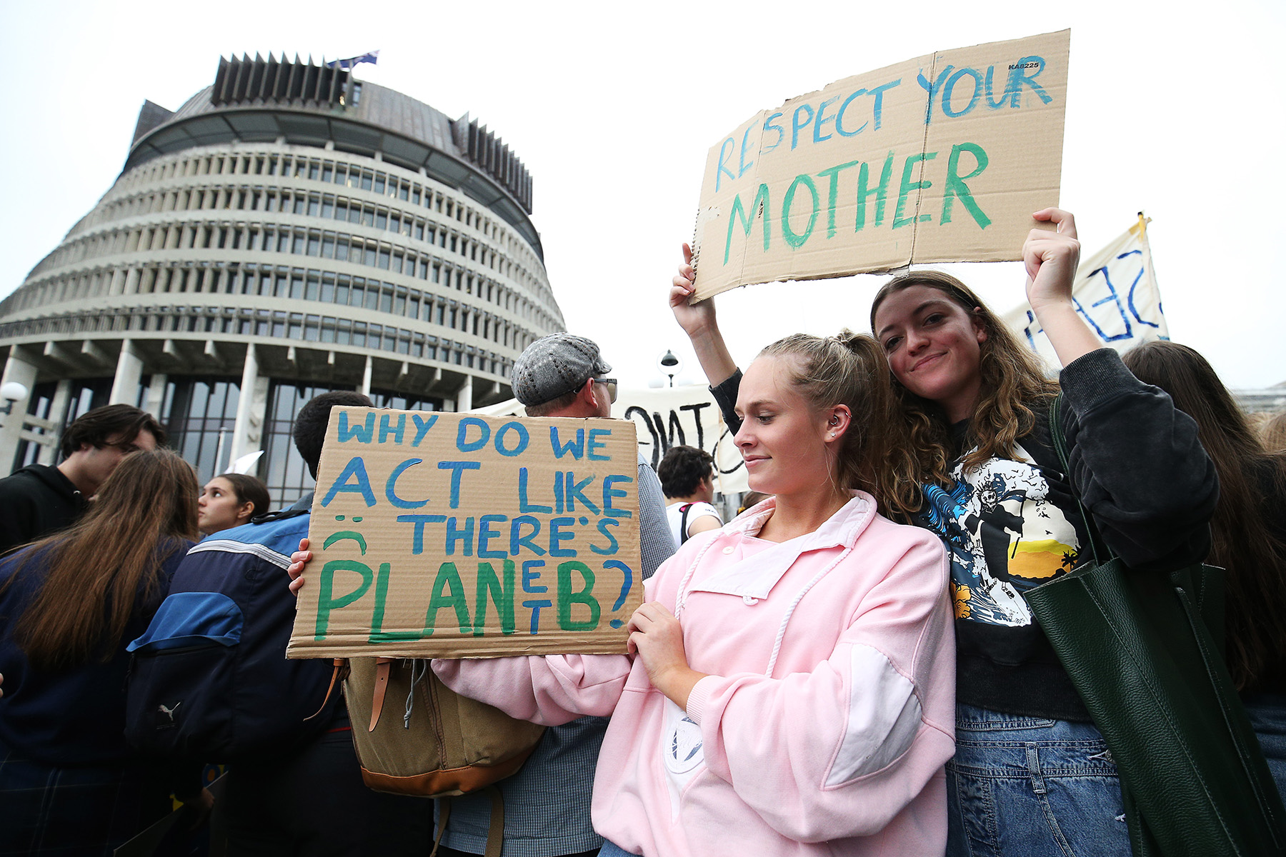 Two student protesters holding signs: 'Why do we act like there's planet B' and 'Respect your mother'