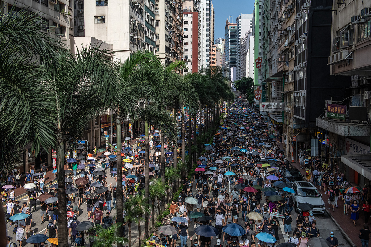 Crowd walking down street lined with palm trees