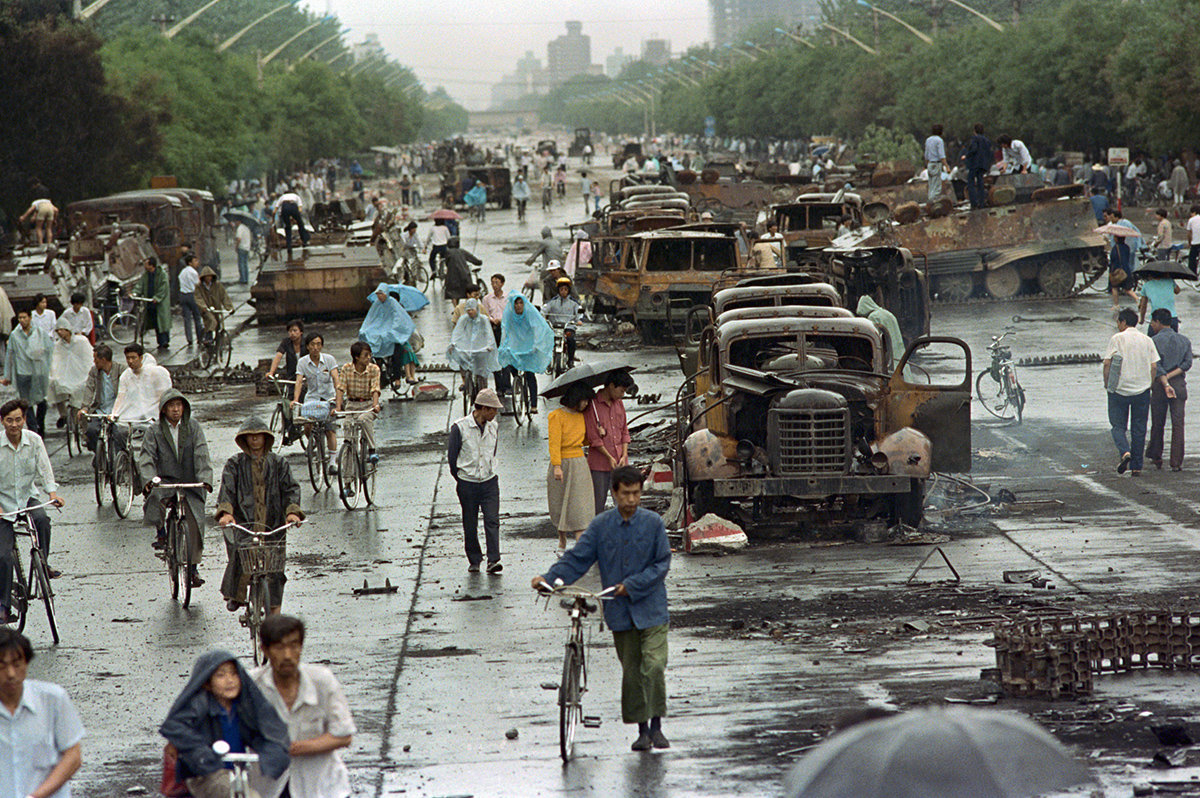 People biking and walking among destroyed vehicles and rubble